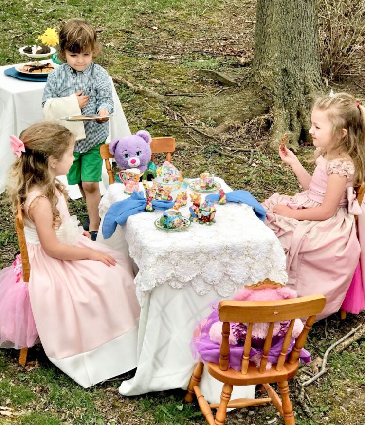 Happy Kids Doing Tea Party With Teddy Bear sitting on wooden chair