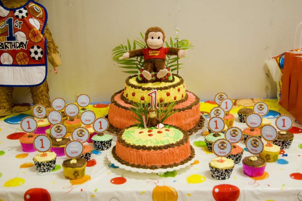 Curious George Birthday party with birthday cake and cupcake on the table