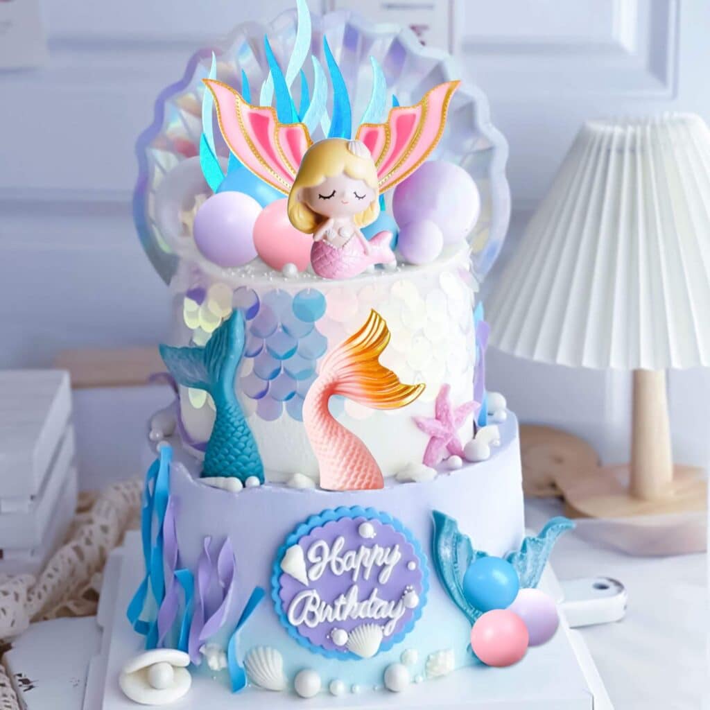 a tiered cake with blue and white gradient icing and mermaid tail