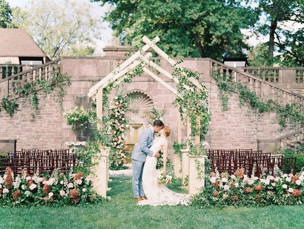 Beautiful Wedding Couple in photoshoot, standing in front of Greenery Arch