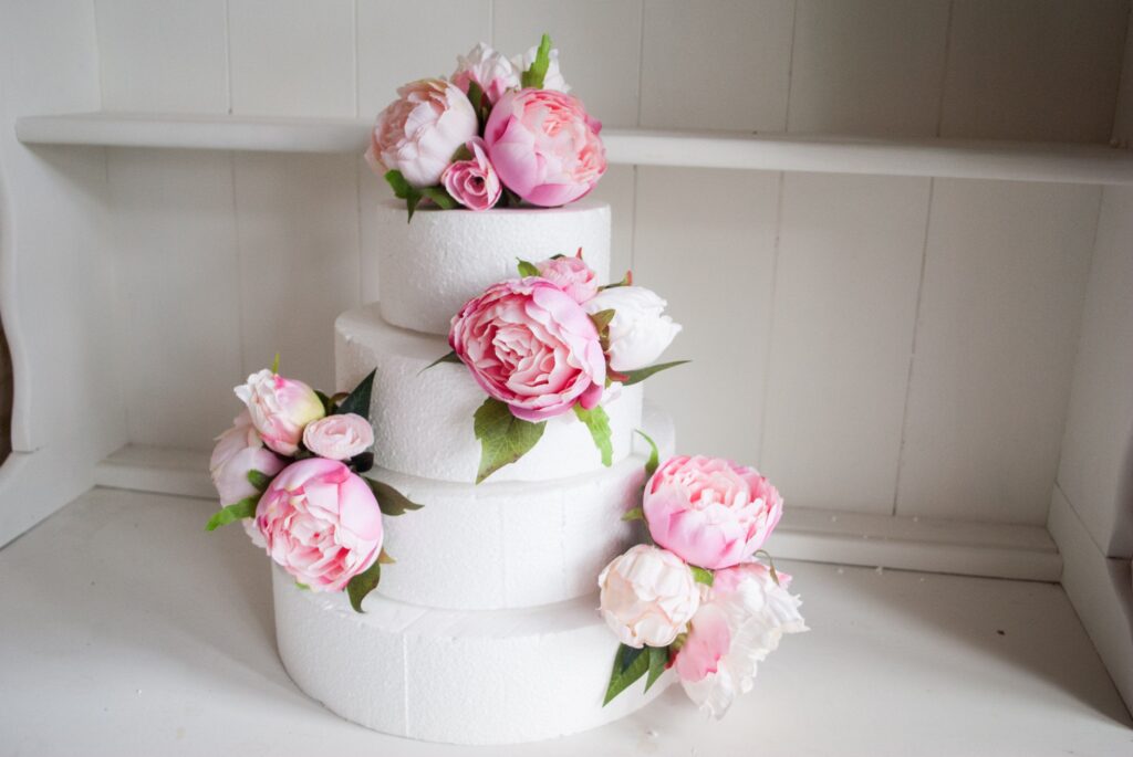 three tiered white frosting wedding cake with fresh peony