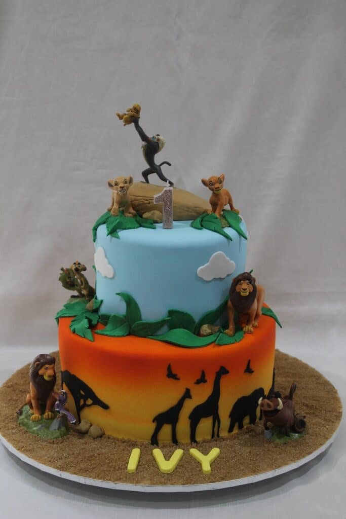 2 tiered green and blue Lion King cake, with giraffe, tree and sky fondant